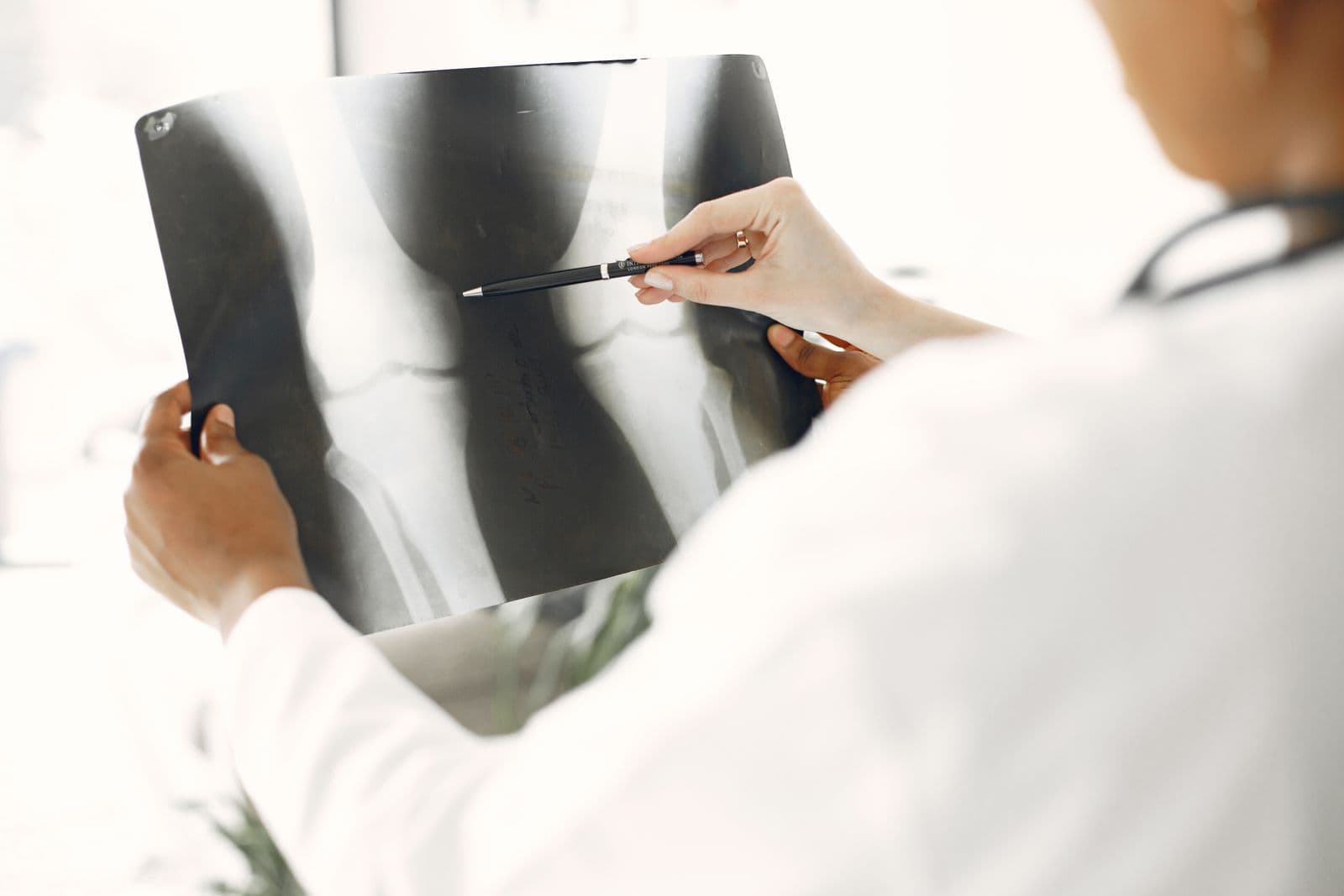 Medical professional closely examining a leg X-ray